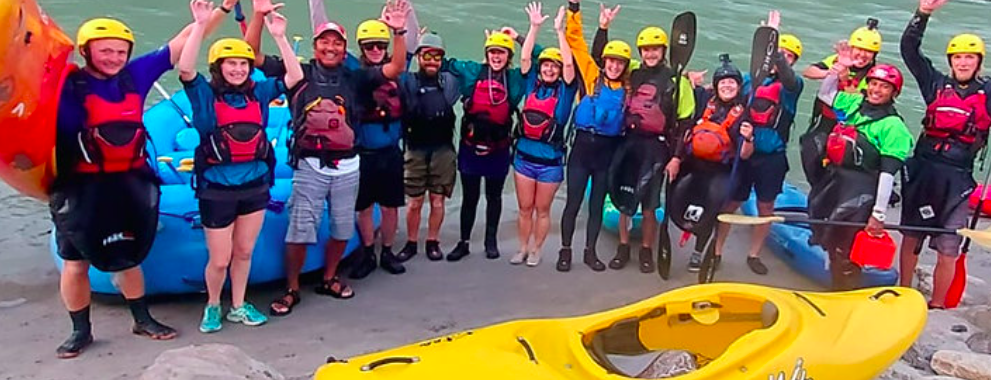 Group of paddlers and instructors beside rafts and kayaks at Royal Beach Camp